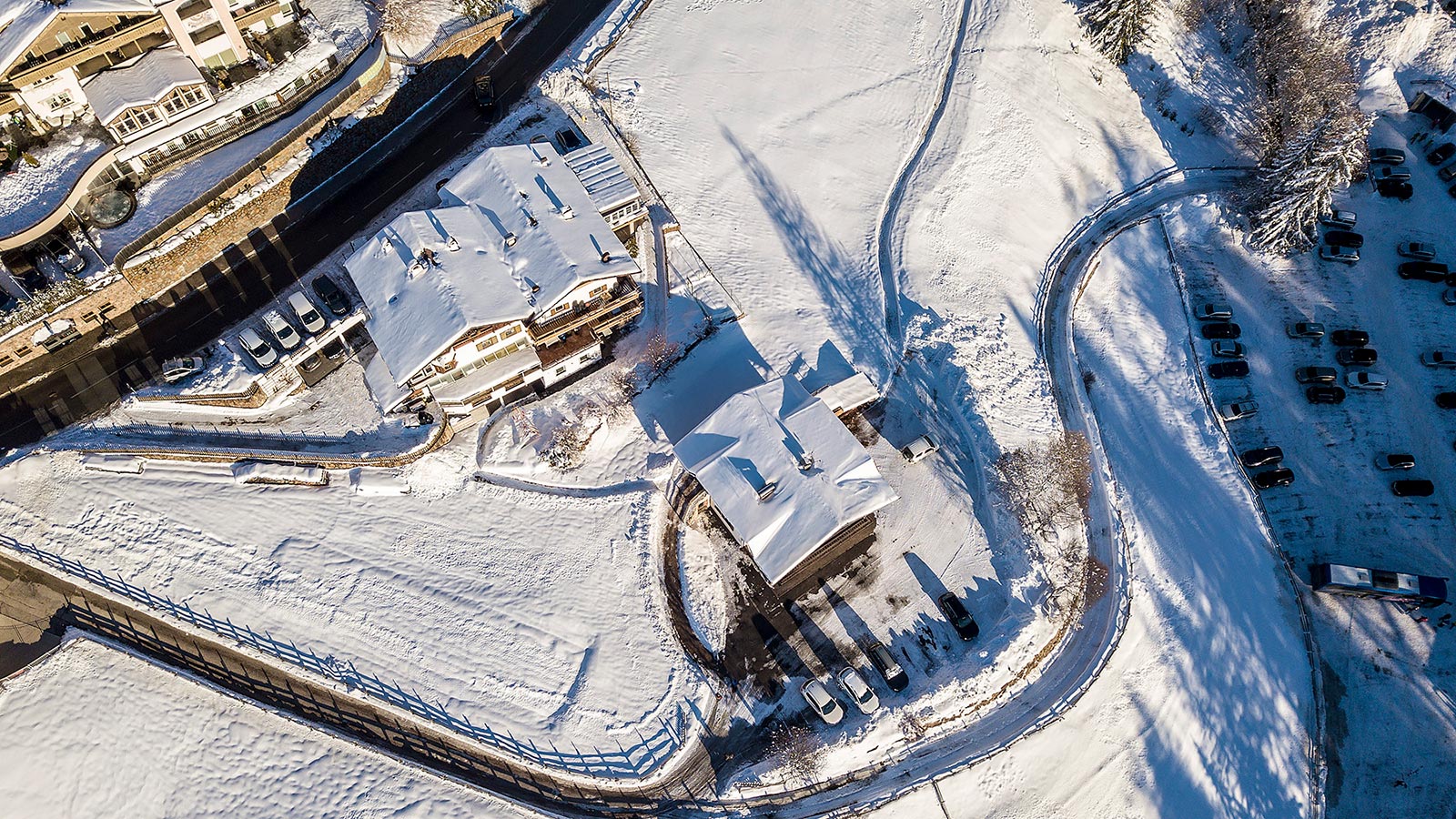 eine Aufnahme von oben vom schneebedeckten Gasthof Specker und den umliegenden Häusern im Winter