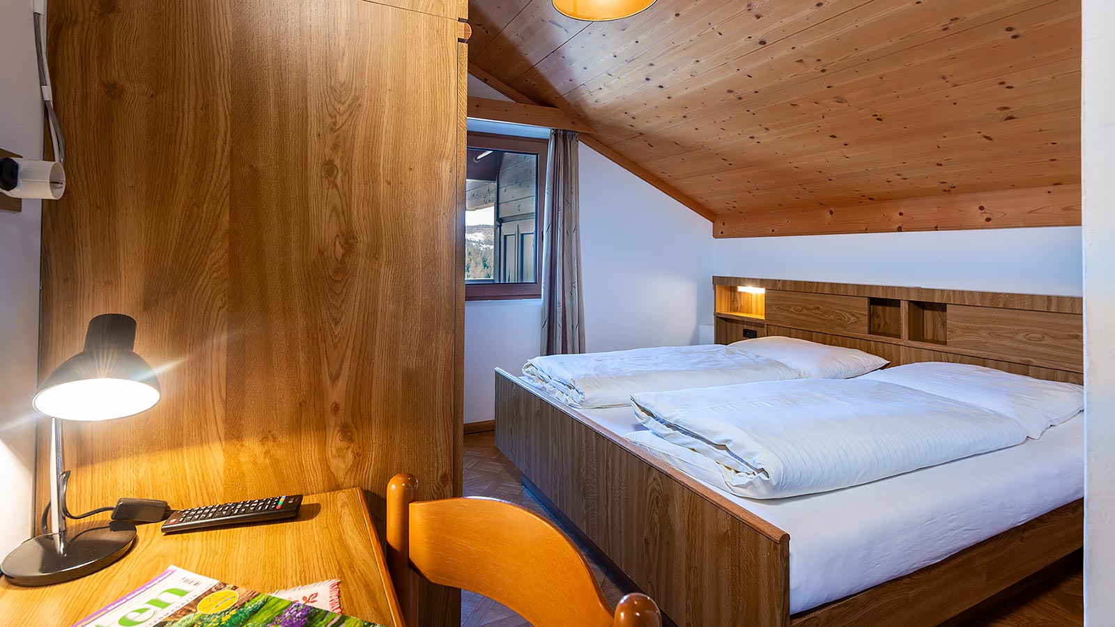 ein in Holz eingerichtetes Zimmer des Gasthof Specker mit Schreibtisch und Tischlampe